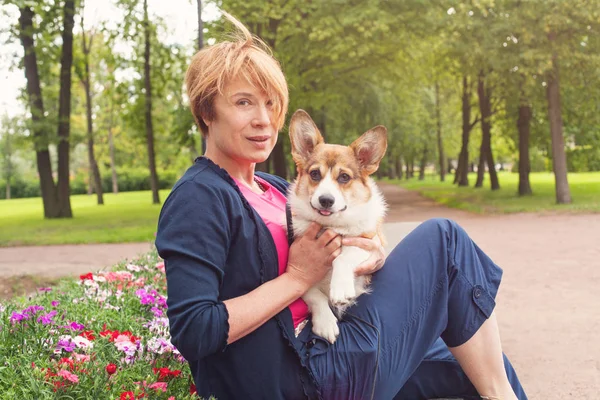 Lycklig kvinna i trädgården med sin hund Corgi — Stockfoto