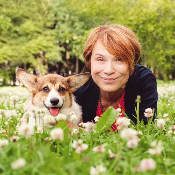 Senior Kvinna med hennes sällskapsdjur vän hund på grönt gräs i sommarpark — Stockfoto