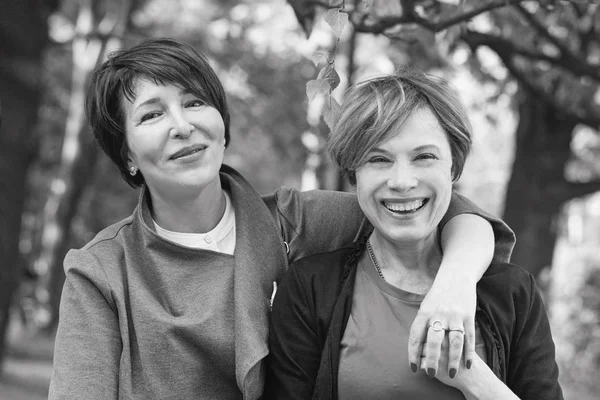Two happy women walking in summer park, black and white portrait — Stock Photo, Image