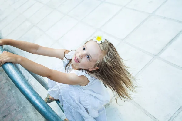 Счастливая девочка в белом платье играет рядом с дорогой — стоковое фото