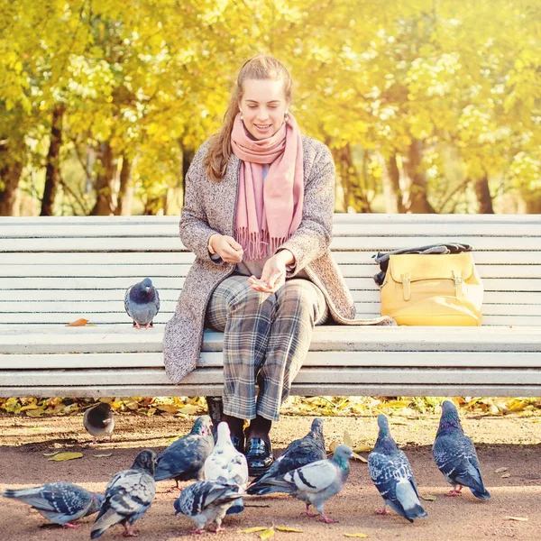 Mooie vrouw rusten in Park en voederen duiven — Stockfoto