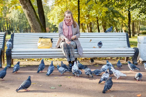 公園で休んで鳩に餌を与えるかわいい女性 — ストック写真