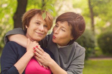 Yaz parkında yürüyen iki mutlu kadın, portre