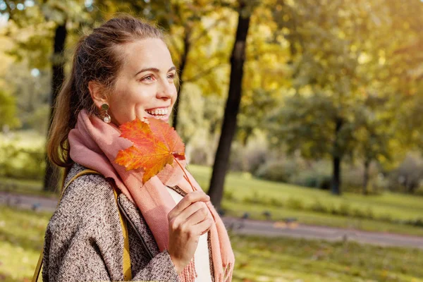 Mignon sourire automne femme tenant la feuille d'érable rouge à l'extérieur . — Photo