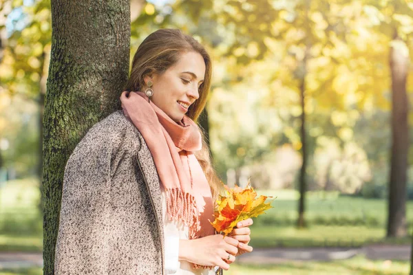 Belle femme souriante rêve et tenant feuille d'érable jaune automne — Photo