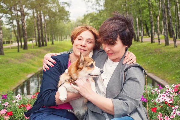 Two mature women with dog pet outdoor, lifestyle portrait