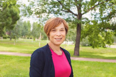 Parkta yürüyen gülümseyen yaşlı kadın. Yaşlı kadın 