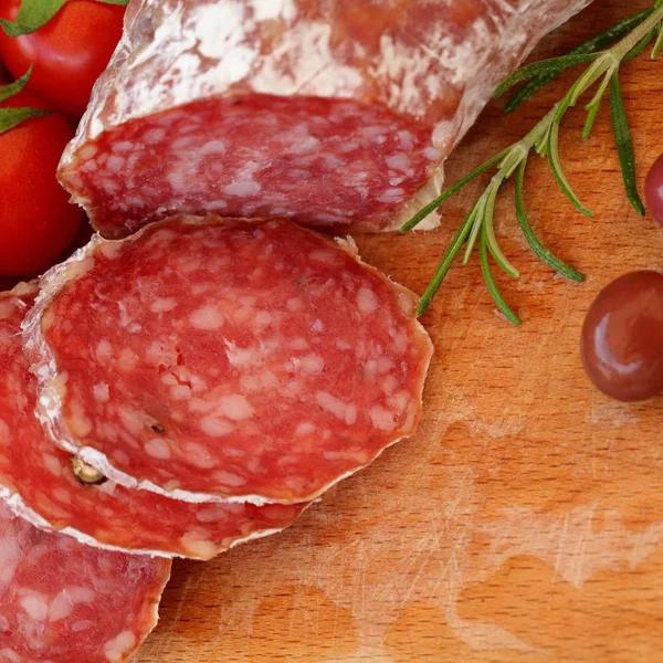 Gastronomische gerechten-salami, olijven en rozemarijn kruiden op houten tafel — Stockfoto