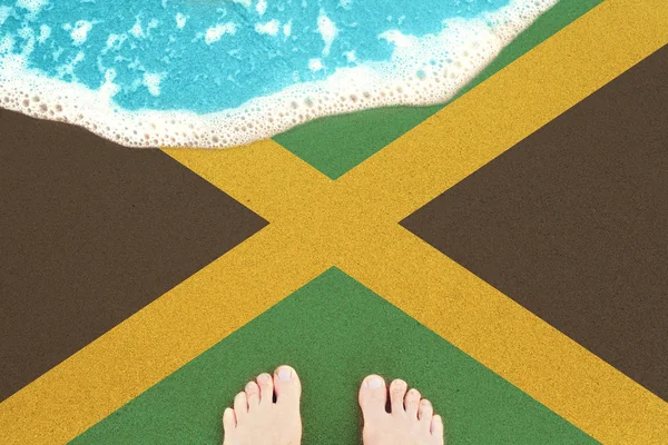 Feet on the sunny sandy beach with flag Jamaica. View from top o — Stock Photo, Image