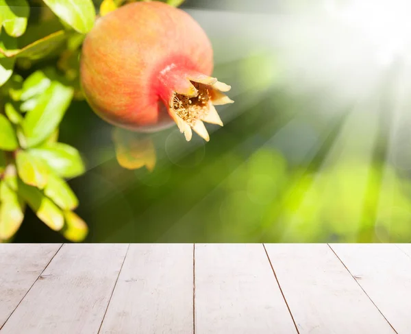 Granatäpple frukt på abstrakta gröna blad och träbord — Stockfoto