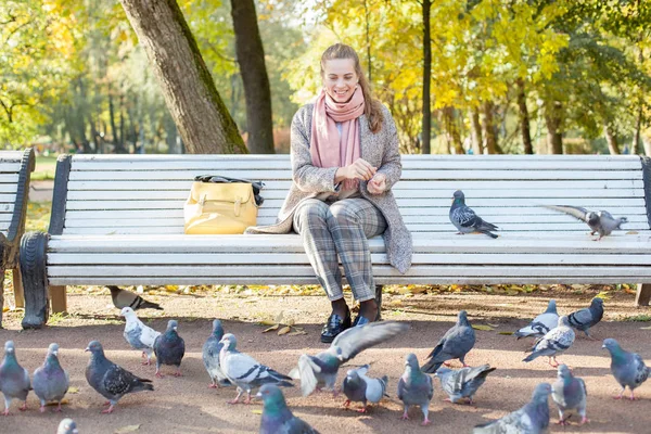 Mooie vrouw rusten in Park en voederen duiven — Stockfoto
