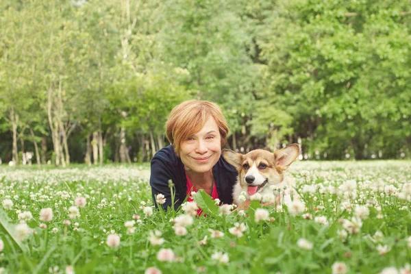 Senior kvinna sitter med hund på grönt gräs — Stockfoto