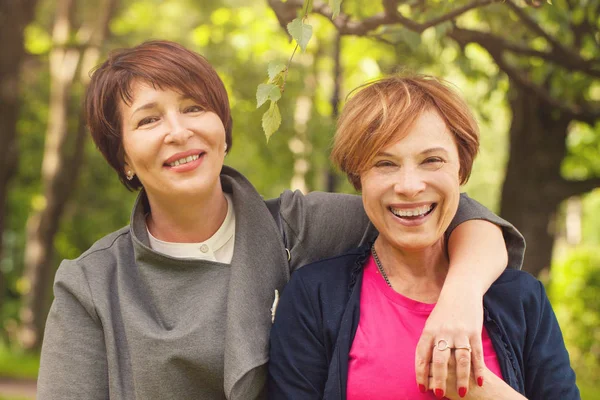 Twee gelukkige vrouwen wandelen in zomerpark, portret — Stockfoto