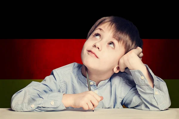 Pensando niño estudiante contra la bandera de Alemania fondo . —  Fotos de Stock