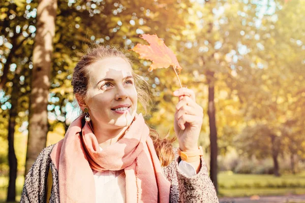 Belle femme d'automne tenant la feuille d'érable jaune à l'extérieur . — Photo