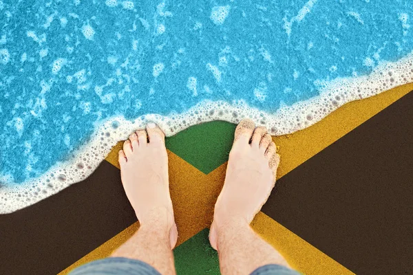 Fötterna på den soliga sandstranden med flagga Jamaica. Topputsikt på Surf — Stockfoto