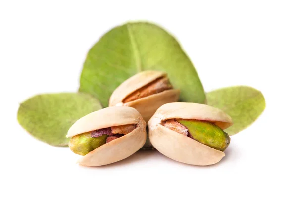 Unas cuantas sabrosas nueces de pistacho con hojas aisladas sobre fondo blanco —  Fotos de Stock