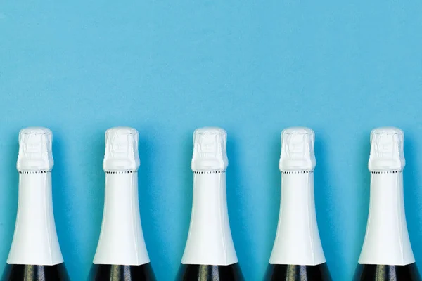 Mousserende wijn fles in rij op blauwe achtergrond. Feestdagen, feest — Stockfoto