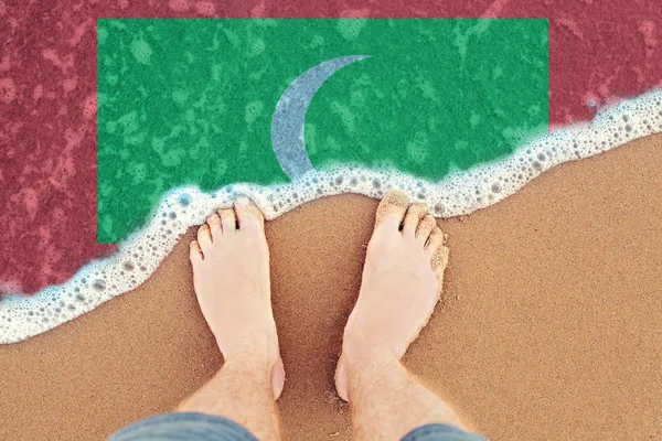 Two Feet on sandy beach with flag Maldives. Top View on sea surf — Stock Photo, Image