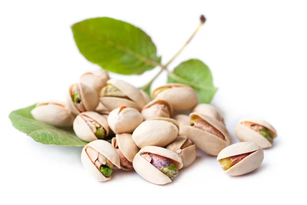Flera läckra pistagenötter med löv isolerade på vitt — Stockfoto