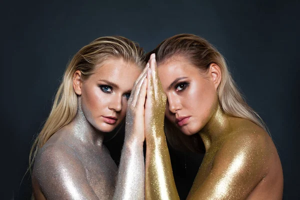 Dos magníficas mujeres modelos con oro y plata maquillaje brillo creativo — Foto de Stock