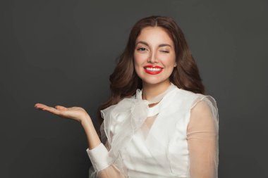 Mutlu gülümseyen kadın göz kırpıyor ve elini boş tutuyor.