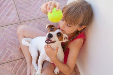 Mutlu kız ve köpek top oynuyorlar.