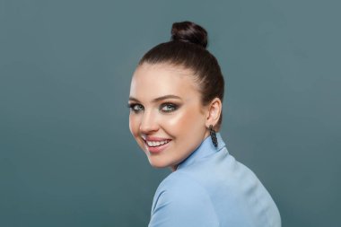 Mavi arka planda gülümseyen güzel bir esmer kadın