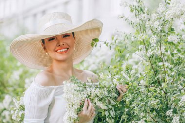 Açık havada beyaz şapkalı, çiçekli güzel kadın portresi.