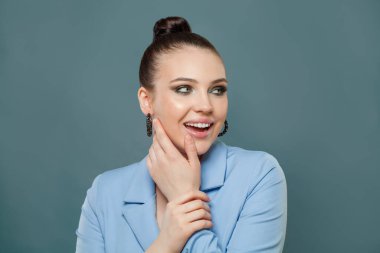 Mavi arka planda gülümseyen hoş bir kadın moda portresi