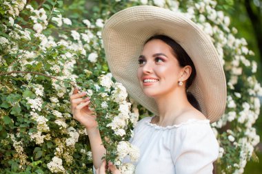 Dışarıdaki çiçeklere bakan genç ve güzel bir kadın.