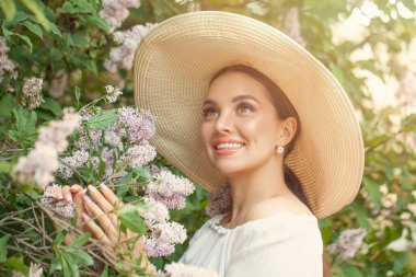 Açık havada çiçekleri olan mutlu genç bir kadın.