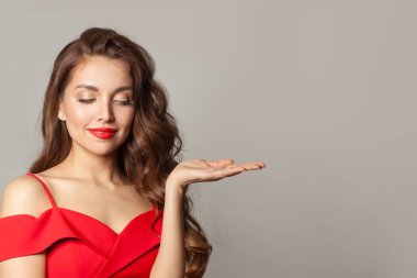 Güzel model kadın boş avuç içini tutuyor ve beyaz arka planda gülümsüyor. 