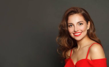 Beauty portrait of brunette woman with trendy make-up and brown curly hair wavy hairstyle and red lips makeup on black background 