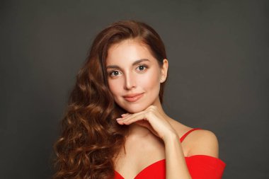 Good-looking brunette woman with trendy make-up and brown curly hair wavy hairstyle and red lips makeup on black background 
