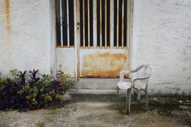 Plastik sandalye ve paslı kapı. Terk edilmiş evde yard.