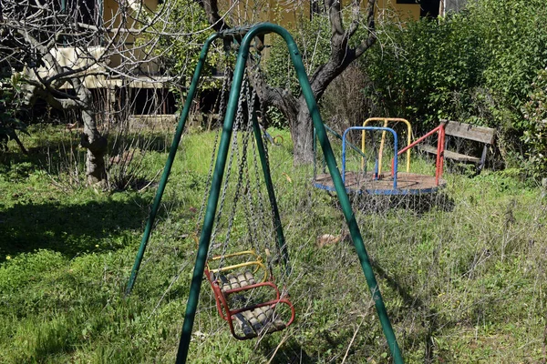 Playground abandonado velhos balanços e alegre-go-round — Fotografia de Stock