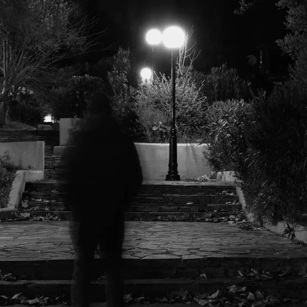 Розмита чоловіча фігура, що йде в парку з лампочками вночі — стокове фото