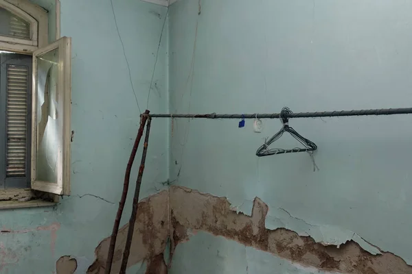 Geïmproviseerde waslijn met roestige hangers in vervallen blauwe kamer — Stockfoto