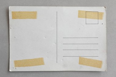 Üzerinde delikler ve yapışkan bant lekeleri olan buruşuk bir kartpostal. Arkaplan dokusu.