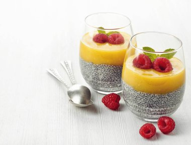 Sağlıklı vegan chia pudingle mango sos ve taze ahududu Beyaz ahşap zemin üzerinde