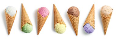 Beyaz arka planda izole edilmiş waffle külahlarında farklı dondurma kepçeleri. Vanilya, fıstık, çilek, karamel, mango, yabanmersini ve çikolata aromalı.