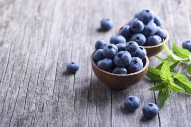 Rustik ahşap masa üzerinde taze yaban mersini kase. Sağlıklı organik mevsimlik meyve arka plan. Organik gıda yaban mersini ve nane yaprağı sağlıklı yaşam için.