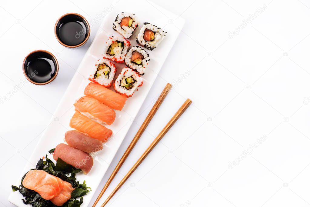 Sushi rolls set with salmon and tuna fish isolated on white background from above. Top view of traditional japanese cuisine. Asian food with chopsticks design.