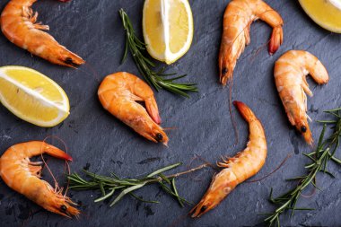 Siyah arka plan üzerine üstten görünüm karides limon ve biberiye. Deniz ürünleri yemek pişirme arka plan.