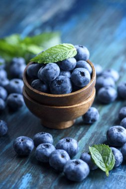 Rustik ahşap masa üzerinde taze yaban mersini kase. Sağlıklı organik mevsimlik meyve arka plan. Organik gıda yaban mersini ve nane yaprağı sağlıklı yaşam için.