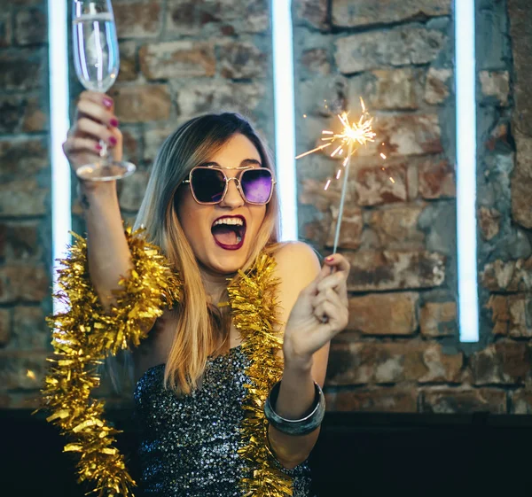 Young happy woman celebrating new year eve drinking champagne with fireworks. Lady clubber in nightclub having fun. Hipster girl at celebration luxury party.