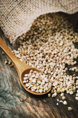 Buğday tahıl yığın halinde vintage ahşap masa arka plan üzerinde tahta kaşık ile natürmort. Organik sağlıklı beslenme mutfağı. Vegan gluten ücretsiz buğday tahıl Diyet.