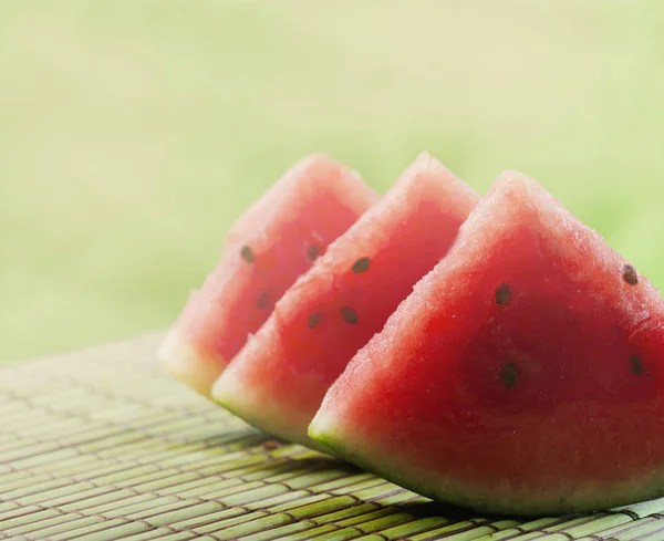 甘い赤スイカのクローズ アップは 日光と庭の緑のテーブル背景にスライスします 夏のさわやかな甘い食べ物 カラフルな果物のある静物 — ストック写真