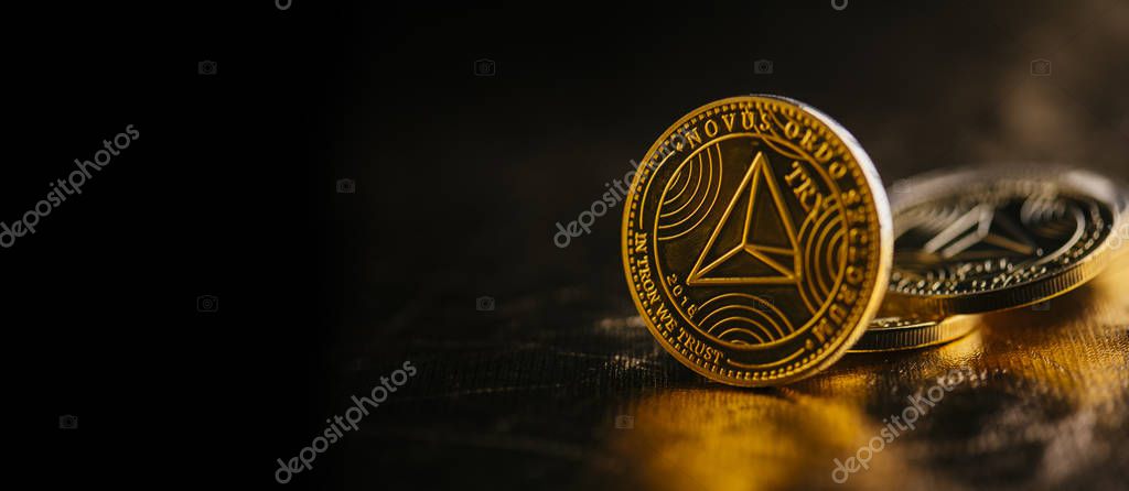 Closeup of golden tron coin TRX cryptocurrency over black and gold background. Virtual money altcoin and blockchain concept.
